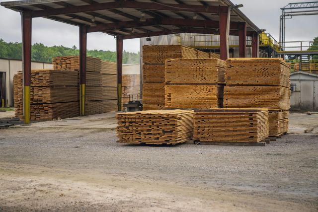 Stacks of timber planks at an outdoor lumber yard, showcasing construction supplies.