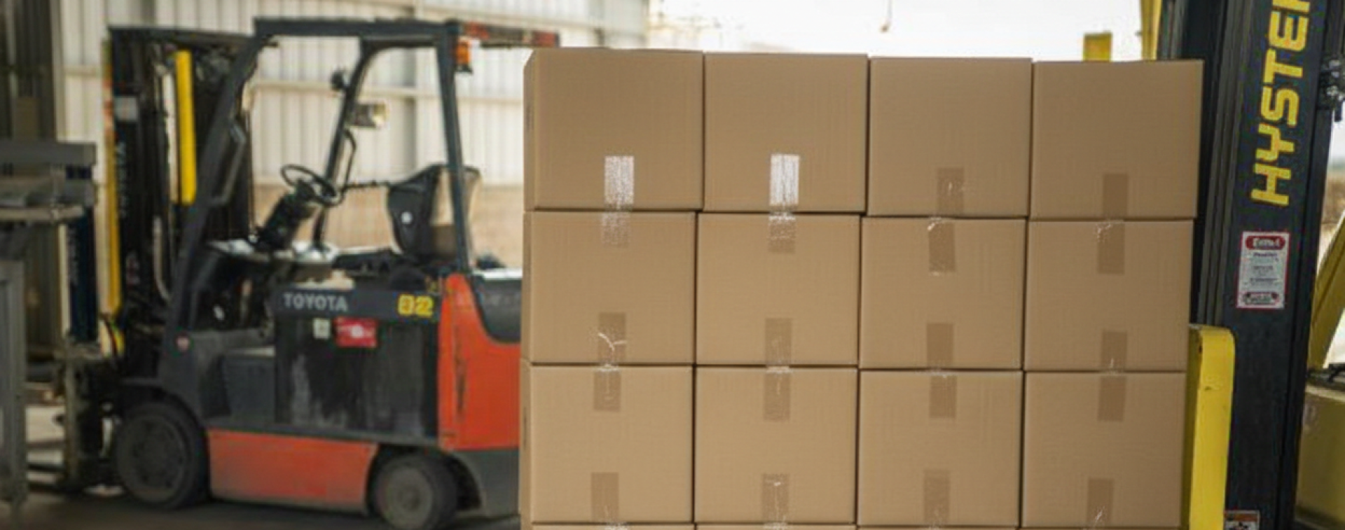 Forklift managing stacks of organic broccoli boxes for shipment in a warehouse setting.